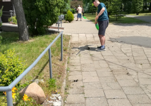 Uczestnik programu zamiata wejście przed budynkiem internatu